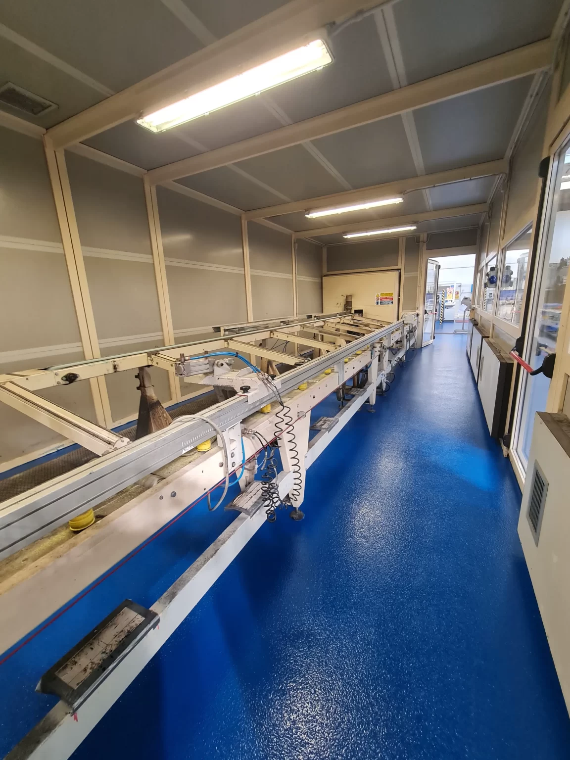 Interno industriale con pavimento in resina blu lucido e antiscivolo, macchinari da lavoro.
